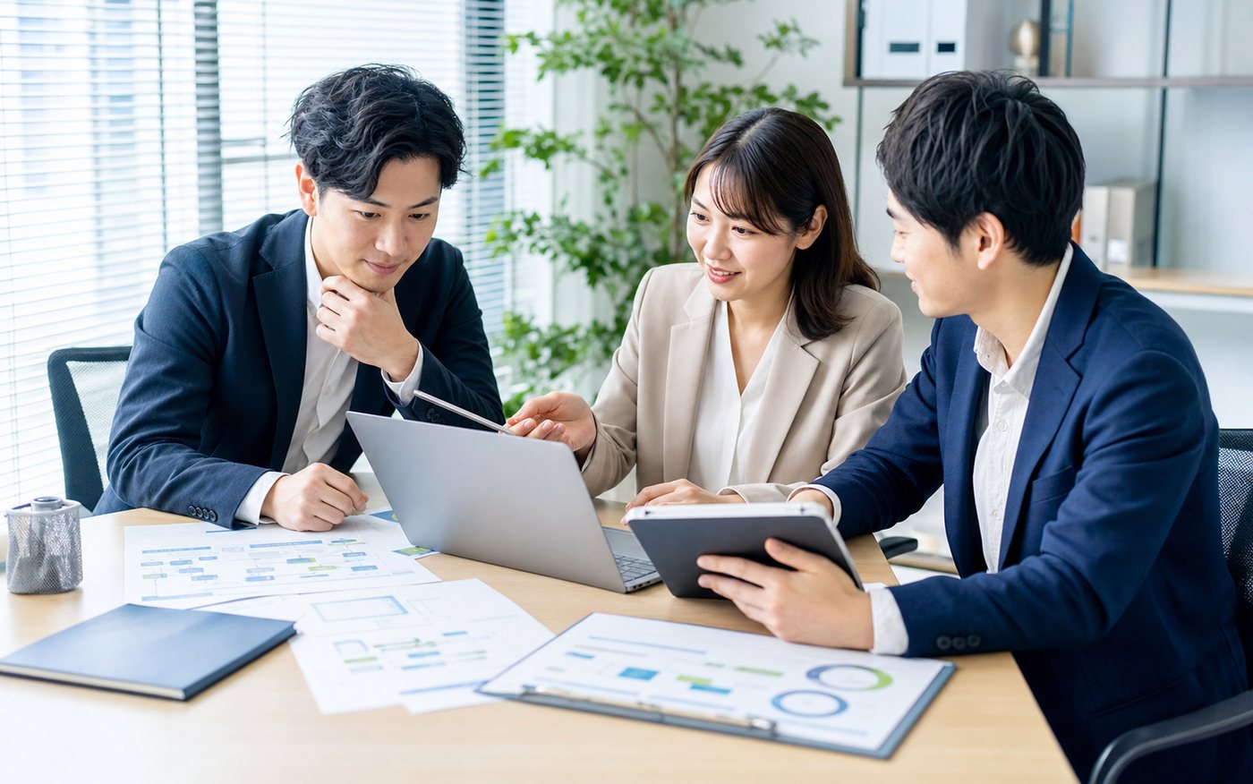 ノートPCと資料を囲んで業務改善について話し合っているチーム