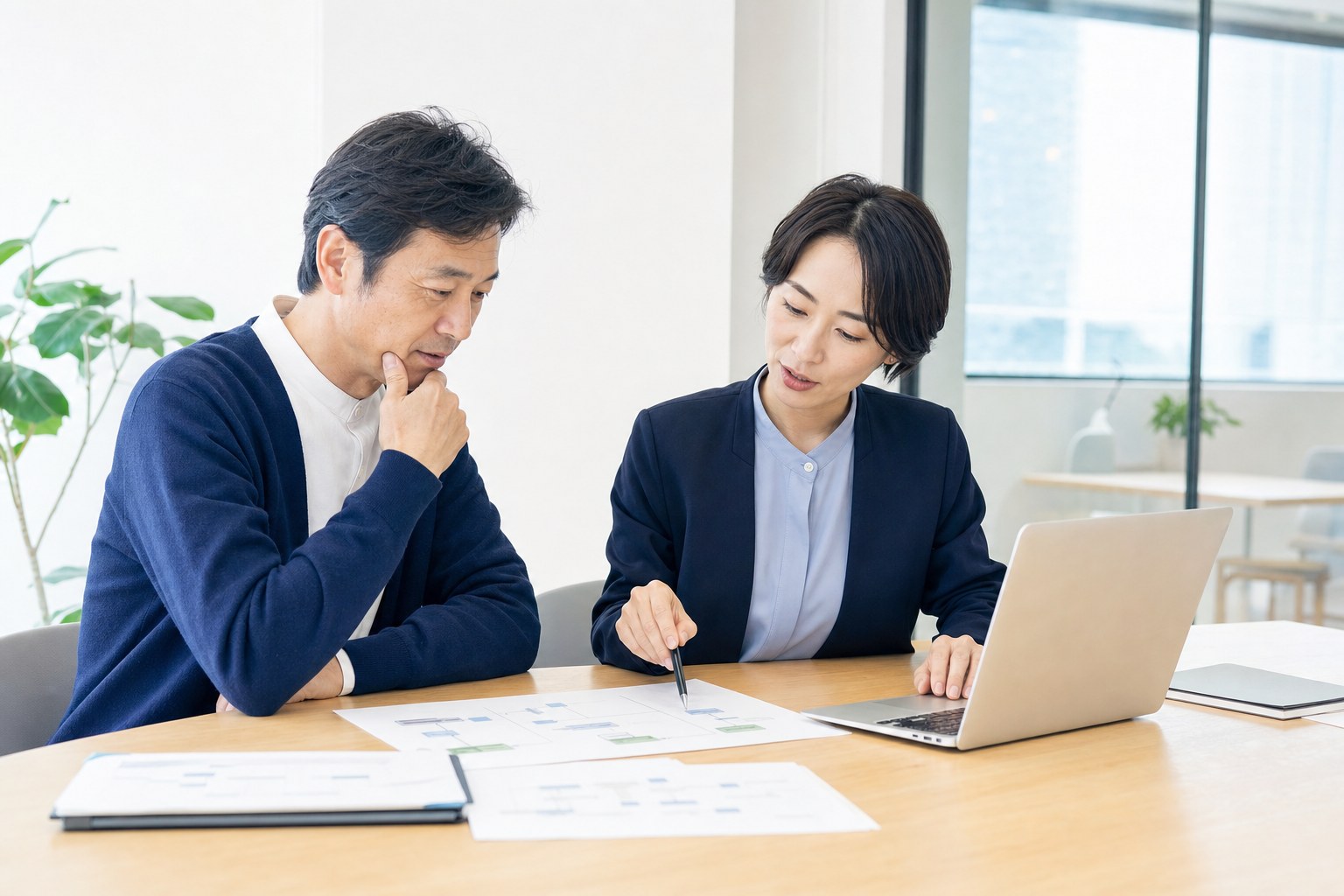 ノートPCと紙資料を見ながら福祉介護事業の業務フローを整理している打ち合わせ風景